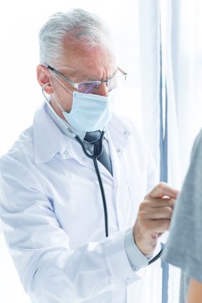 doctor en mascara que examina el paciente de cosecha