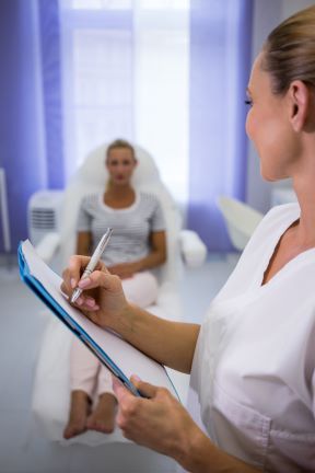 doctor escribiendo informes medicos mientras habla con el paciente