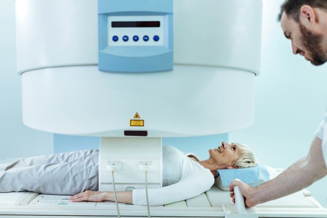 mujer madura feliz que tiene un examen de resonancia magnetica del abdomen en el hospital